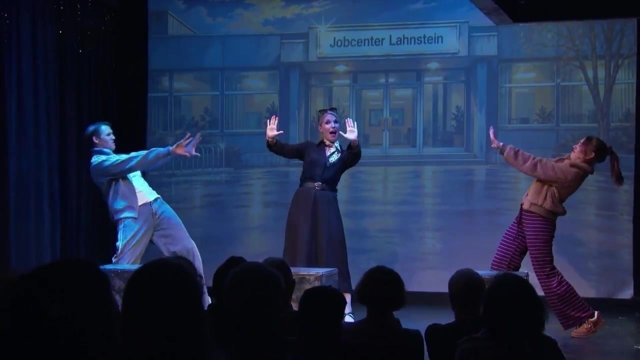 Petra, Maurice und Bibi im Kostüm auf der Bühne vor dem Jobcenter Lahnstein – Szene aus Lahnrock Airways